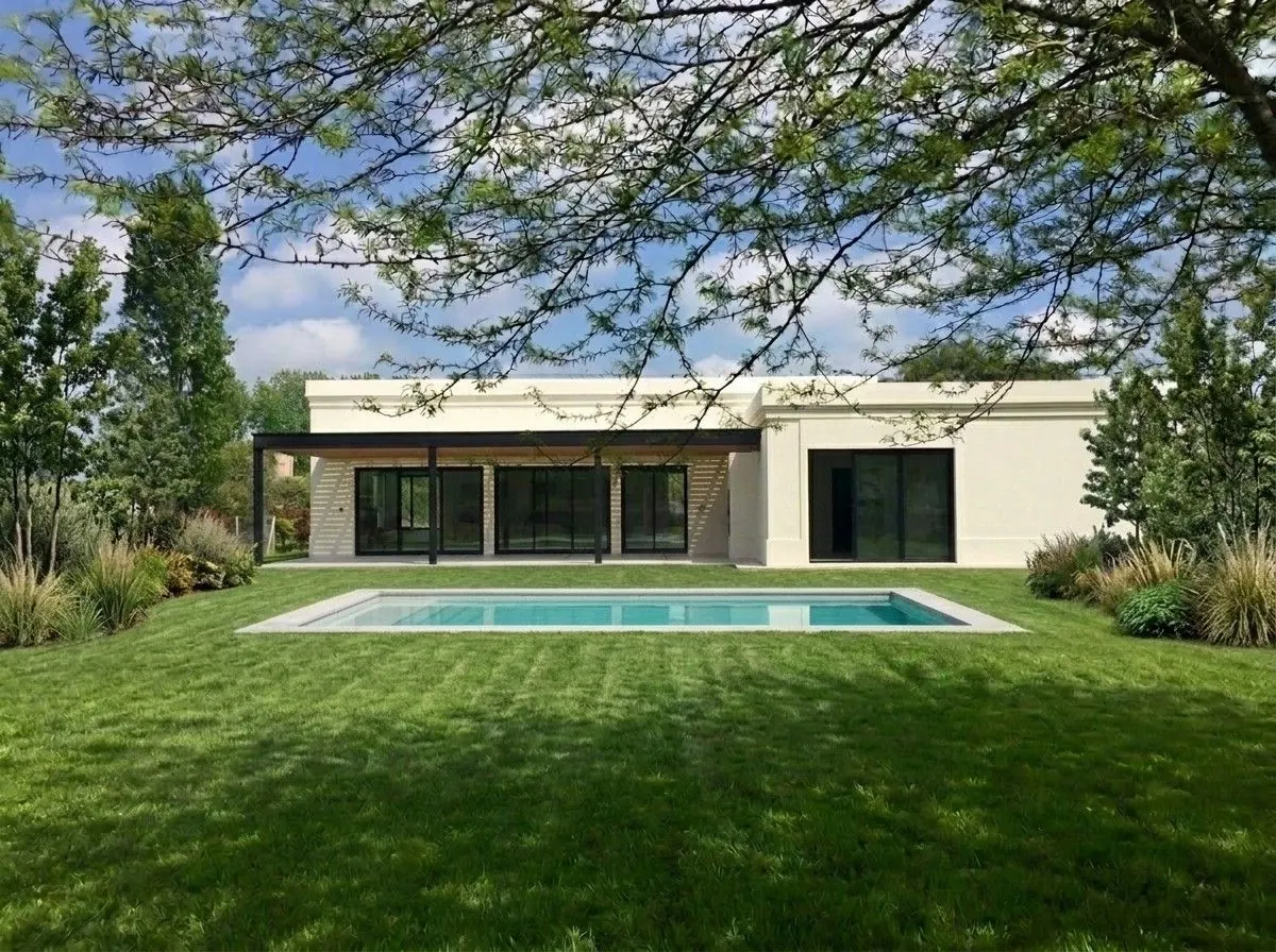 Frente al parque: casa de una planta con galería, aberturas de piso a techo y pileta sobre el césped