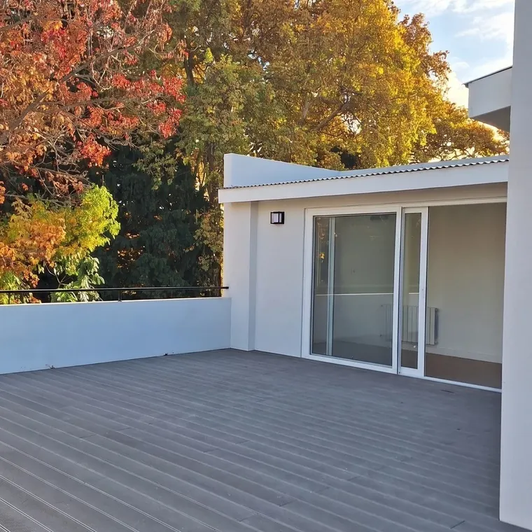 La terraza terminada, con el deck gris y el ventanal corredizo que la conecta con el interior