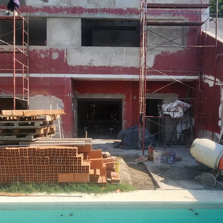 La fachada al parque durante la obra: revoques picados, andamios y los vanos nuevos ya abiertos con sus dinteles