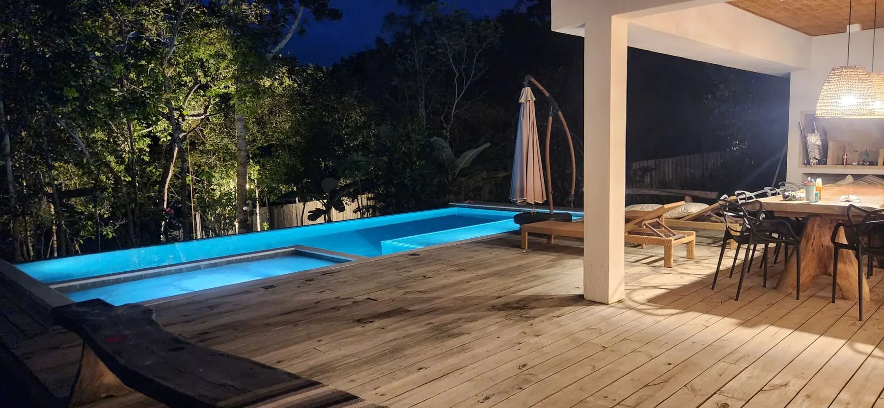 La pileta iluminada de noche y la galería con el comedor bajo techo